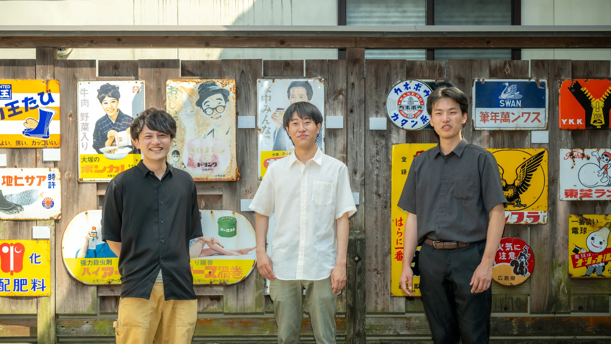 新温泉町の昔の看板が並ぶ商店の前に立つYuiの3人